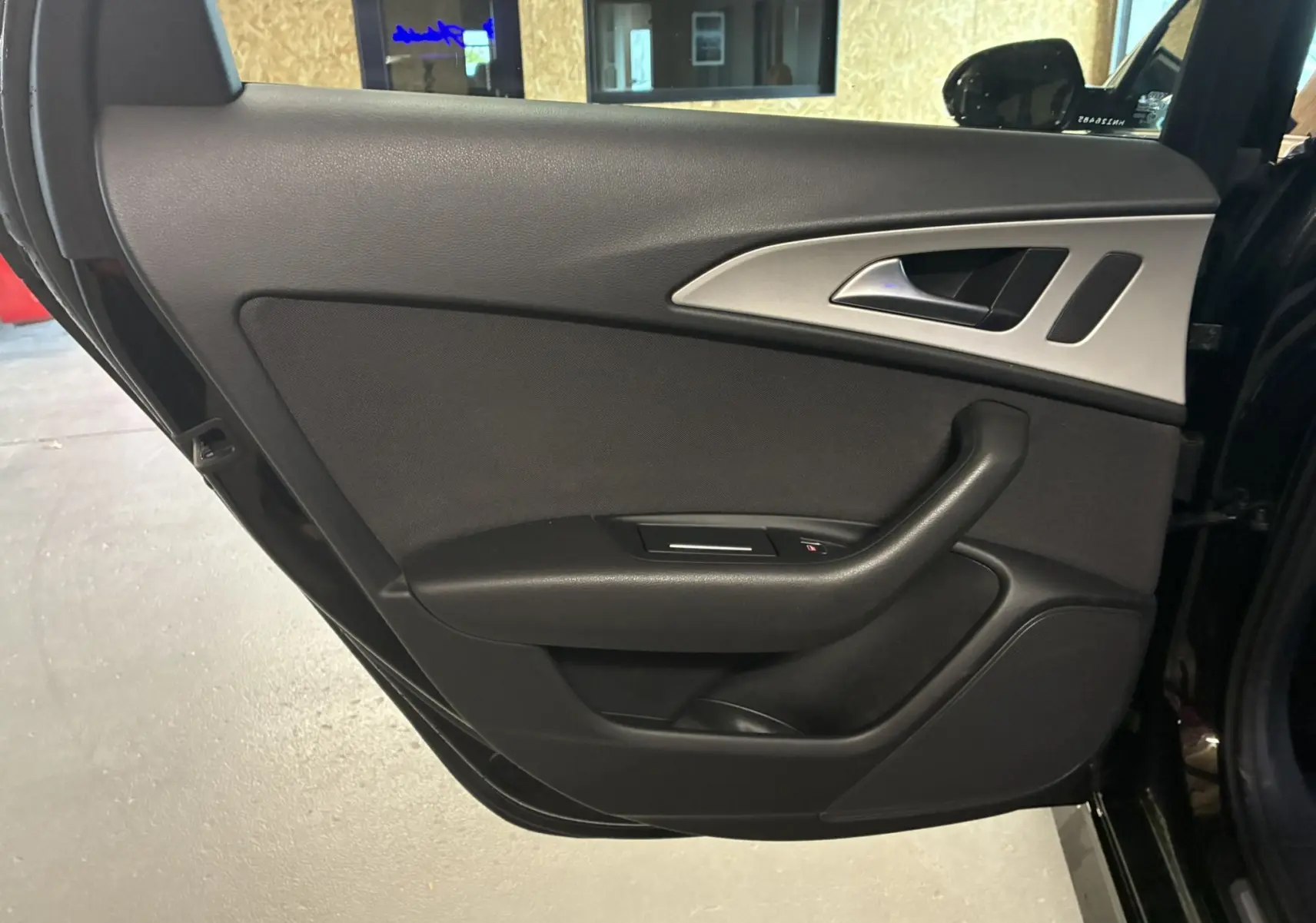 Vue intérieure de la porte arrière gauche noire de l'Audi A6 Avant 2.0 TDI 2017 avec poignée et commandes de fenêtre.