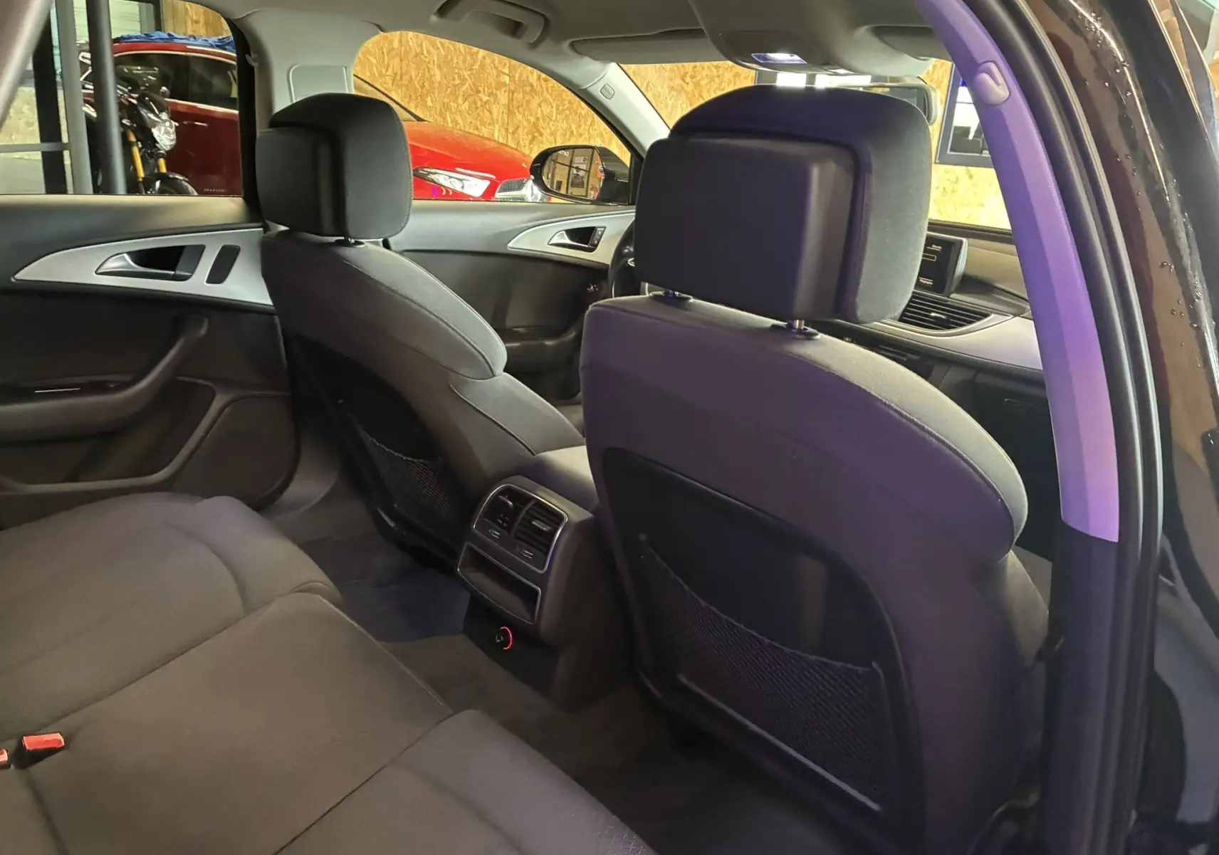 Vue intérieure arrière de l'Audi A6 Avant noire 2017, sièges tissu noir et console centrale avec aérateurs arrière.