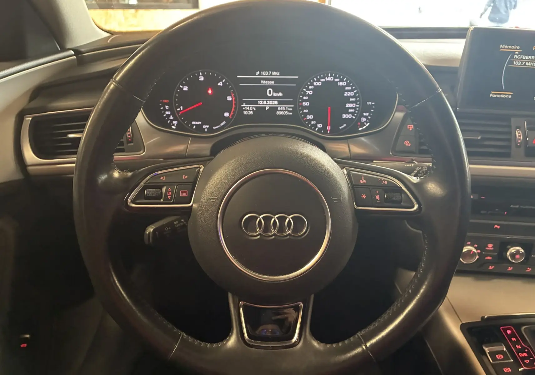 Vue frontale du volant noir en cuir de l'Audi A6 Avant 2017 avec tableau de bord digital et commandes intégrées.