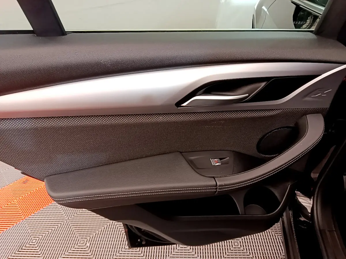 Gros plan sur la porte côté gauche noire du BMW X3 xDrive20d 2020, avec poignée argentée et haut-parleur intégré.