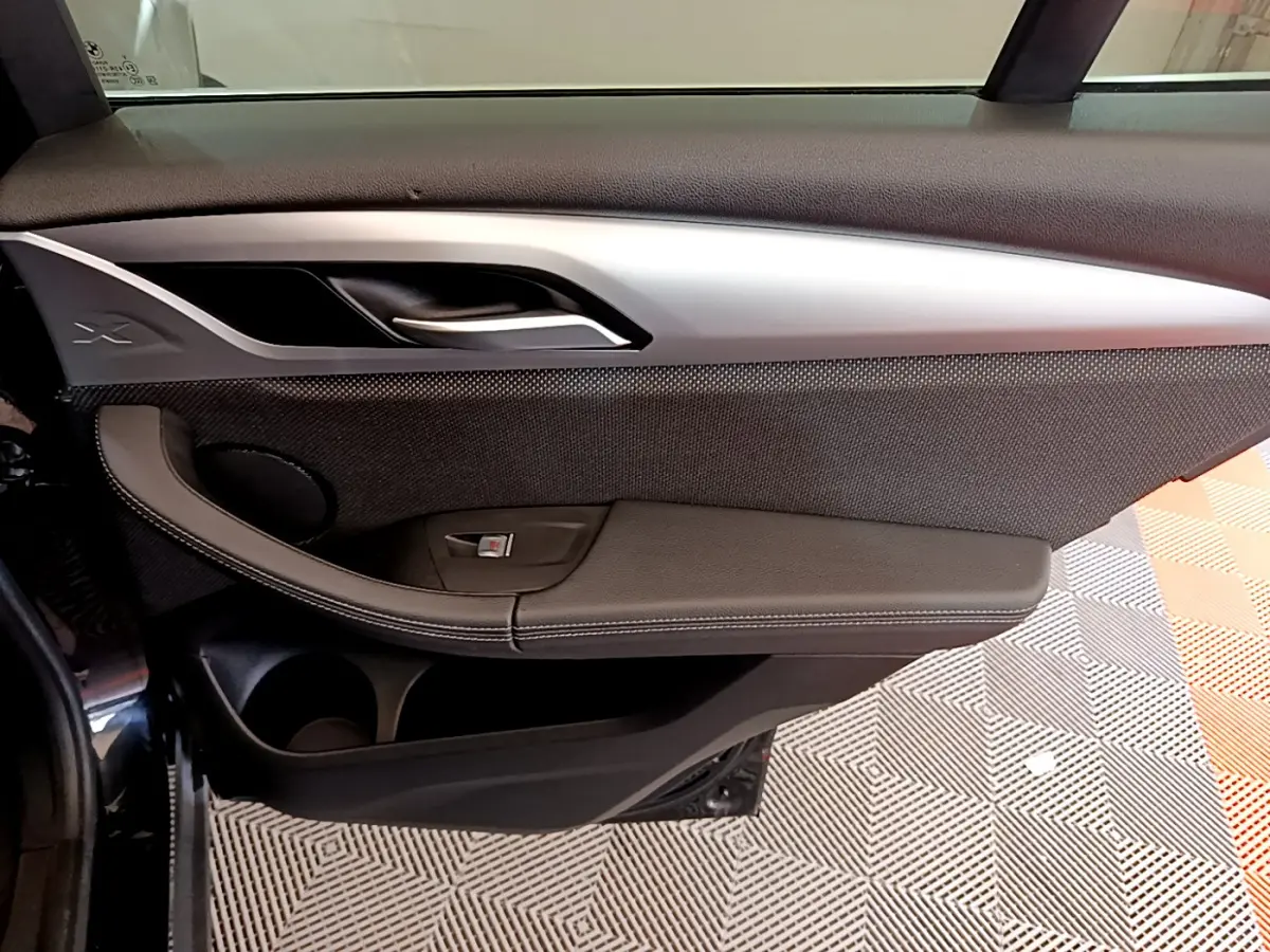 Vue intérieure côté gauche de la porte avant noire du BMW X3 xDrive20d 2020 avec insert argenté et bouton de vitre.