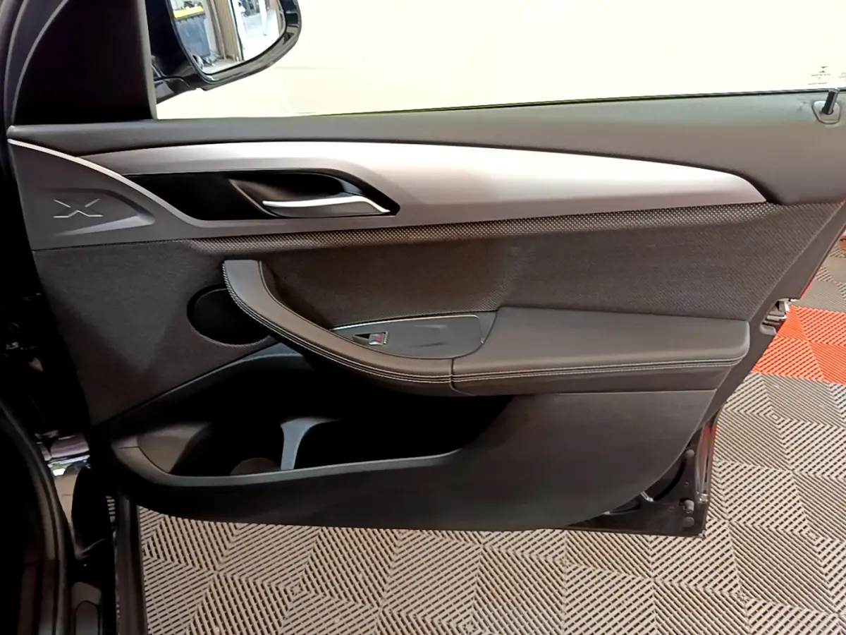 Porte intérieure côté gauche noire de BMW X3 xDrive20d 2020 avec insert argenté et logo X visible.