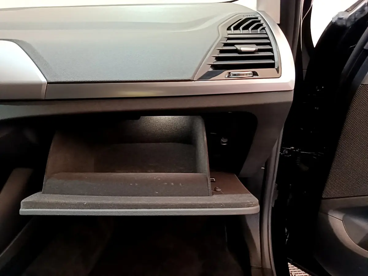 Gros plan sur la boîte à gants ouverte côté passager du BMW X3 xDrive20d noir, montrant le tableau de bord et la portière.
