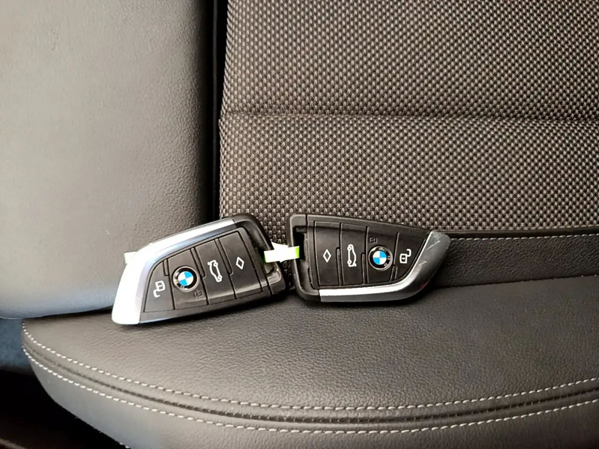 Deux clés BMW posées sur un siège en cuir noir et tissu gris à motifs, intérieur d'un X3 2020 Lounge.