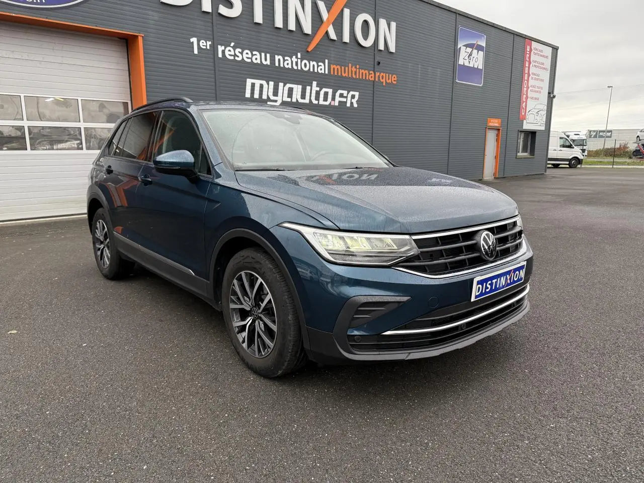 Volkswagen Tiguan 2022 bleu Nightshade en 3/4 avant droit, avec jantes alliage et phares LED allumés.