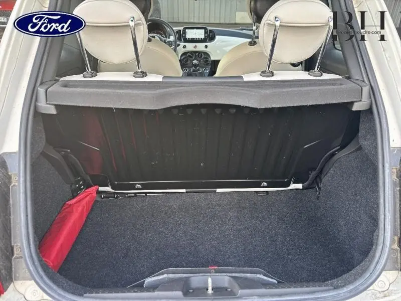 Vue arrière du coffre ouvert d'une FIAT 500 blanche, montrant l'intérieur beige et la tablette cache-bagages.