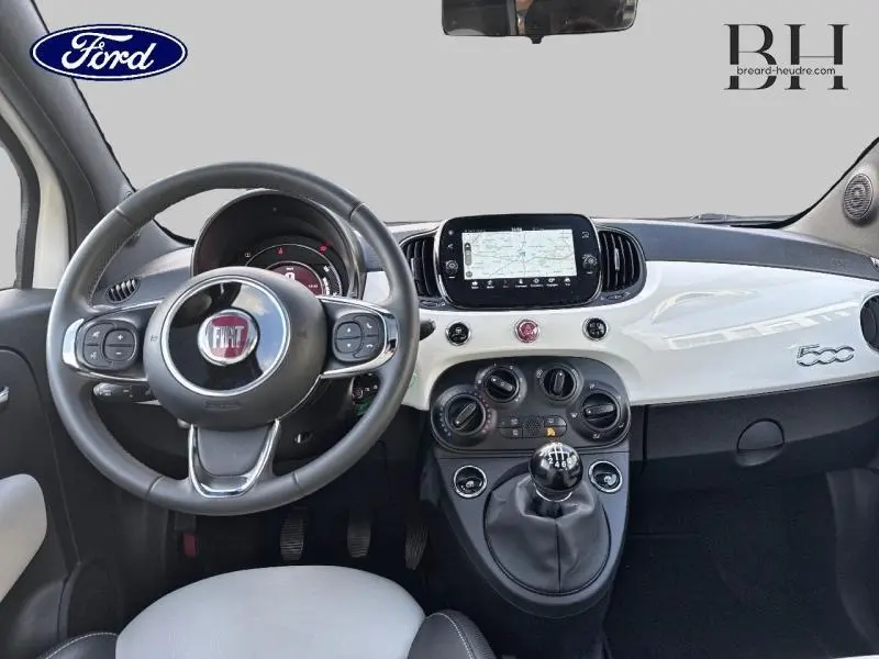 Intérieur avant d'une Fiat 500 blanche, volant cuir multifonction et tableau de bord avec écran tactile central.