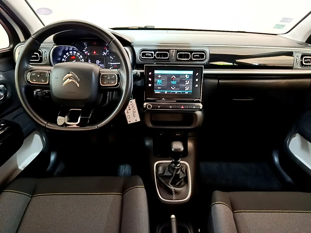 Vue intérieure avant de la Citroën C3 blanche 2019, tableau de bord noir avec écran tactile et volant cuir multifonctions.