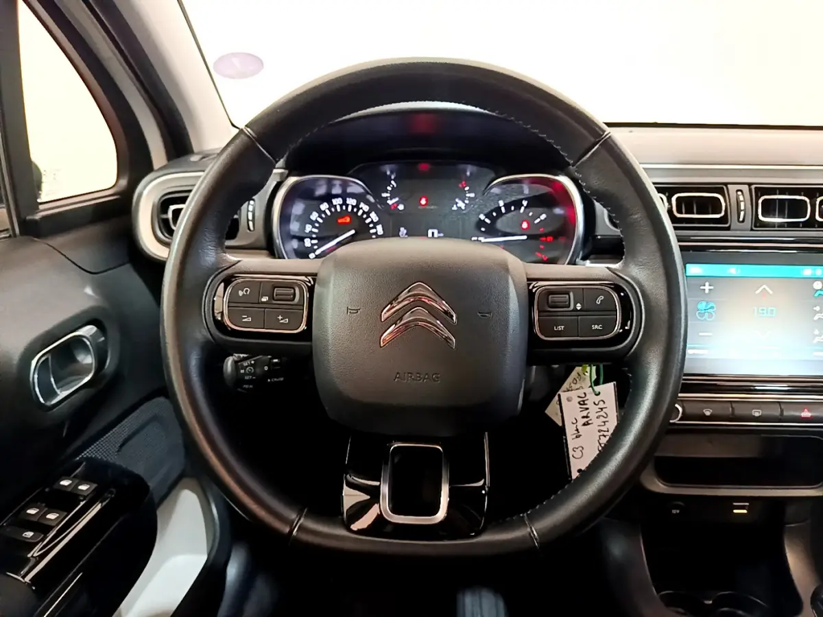 Vue intérieure centrée sur le volant cuir noir de la Citroën C3 blanche avec tableau de bord et écran tactile.