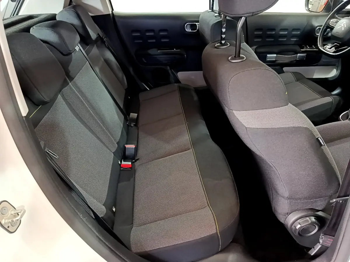 Vue intérieure côté gauche montrant la banquette arrière et partie avant des sièges de la Citroën C3 blanche.