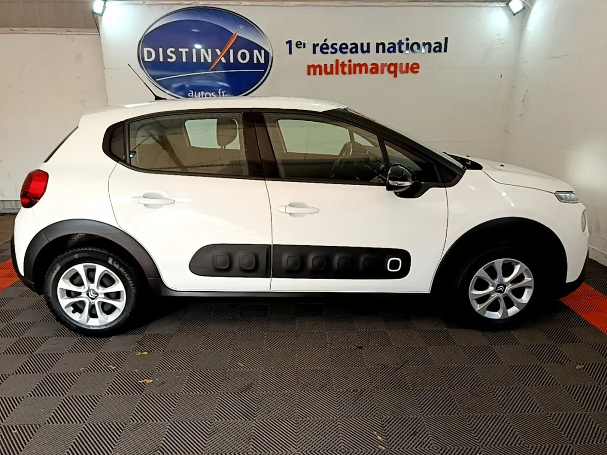 Profil côté gauche d'une Citroën C3 blanche de 2019 avec protections latérales noires caractéristiques et jantes alliage.