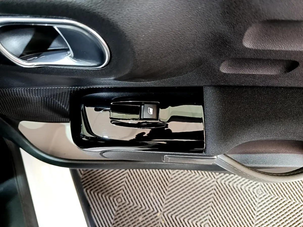 Gros plan sur la commande de lève-vitre côté conducteur noir brillant dans la portière intérieure d'une Citroën C3 blanche de 2019.