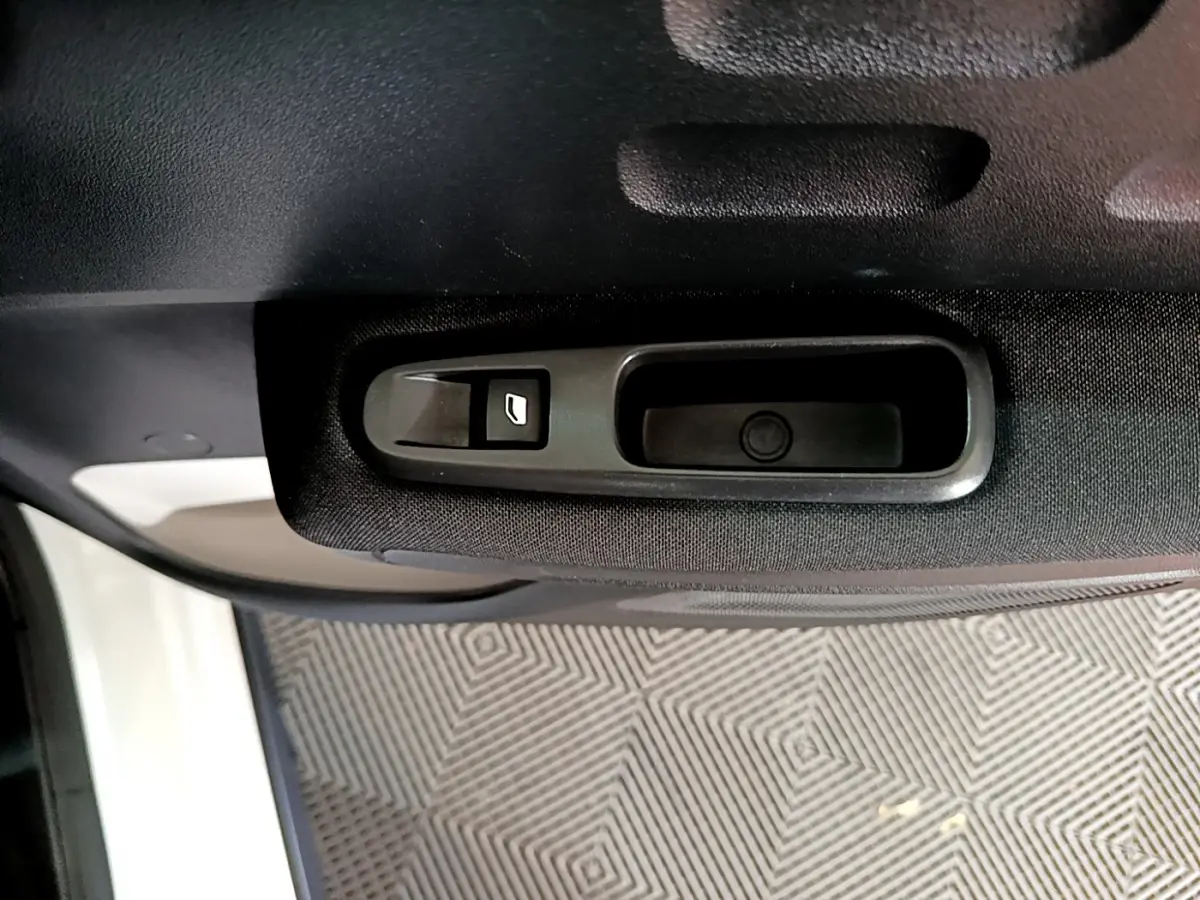 Gros plan sur la commande de lève-vitre côté intérieur d'une porte noire d'une Citroën C3 blanche de 2019.