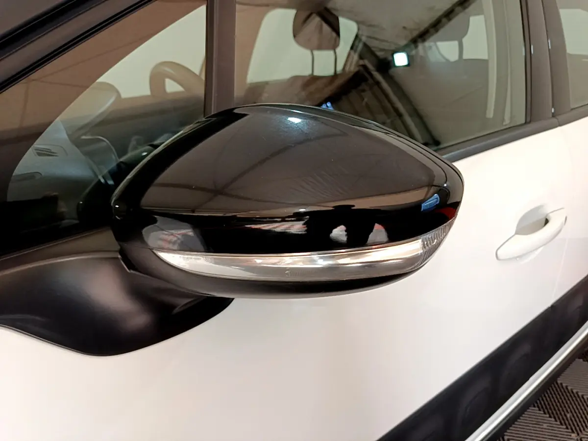 Rétroviseur noir avec clignotant intégré côté gauche d'une Citroën C3 blanche, vue rapprochée du côté conducteur.