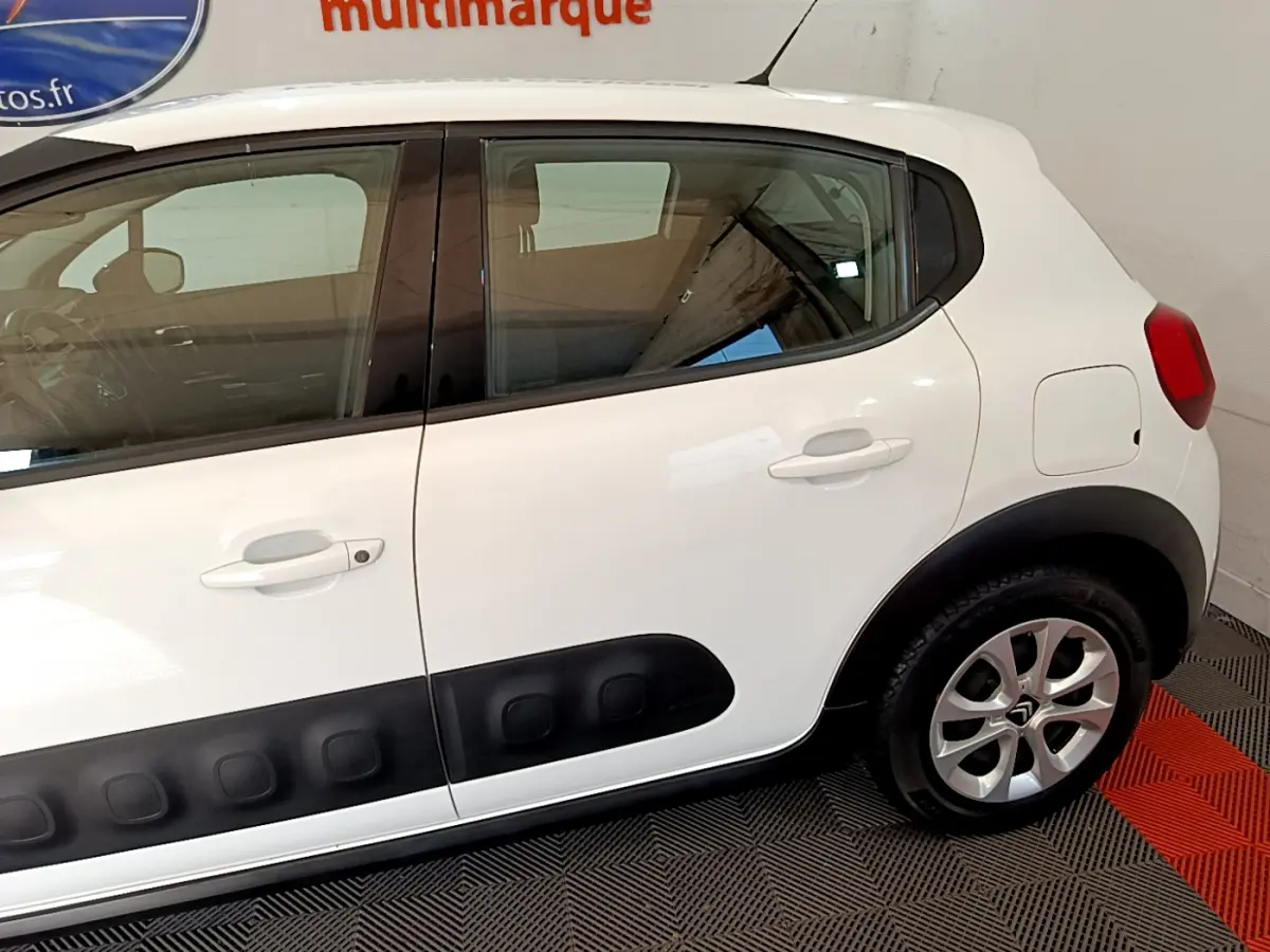 Profil côté droit d'une Citroën C3 blanche avec protections latérales noires et jantes alliage visibles.