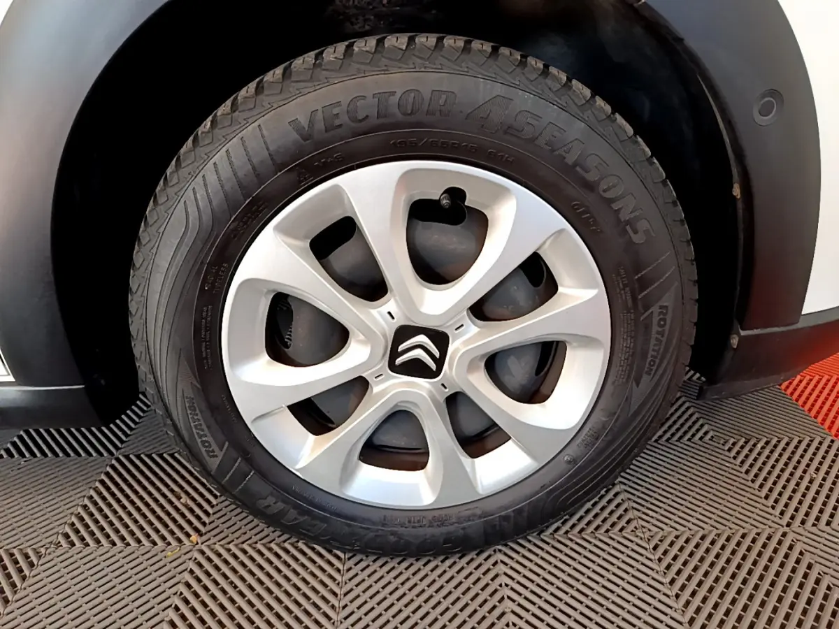 Gros plan sur la roue avant droite d'une Citroën C3 blanche, jante alliage argentée avec logo Citroën central.