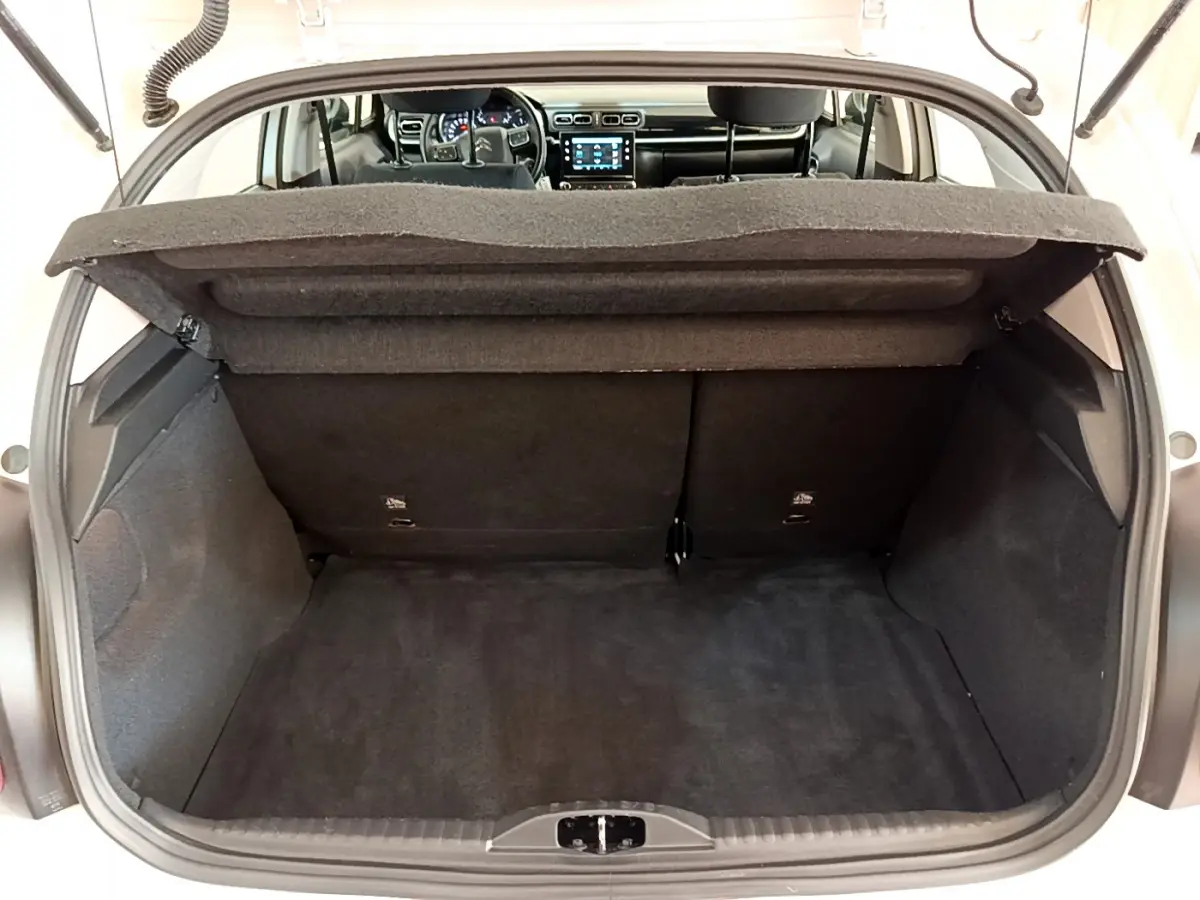 Coffre ouvert d'une Citroën C3 blanche, vue arrière montrant l'intérieur noir et le tableau de bord tactile.