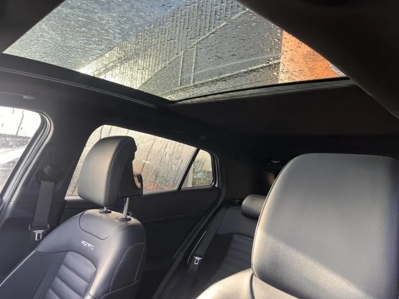 Vue intérieure du toit panoramique et des sièges noirs en cuir GT-Line du Kia Sportage blanc Sensation nacré 2022.