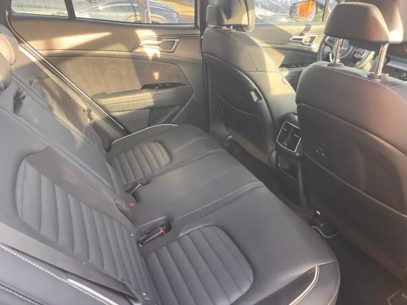 Vue intérieure arrière côté gauche du Kia Sportage 2022, sièges cuir noir avec surpiqûres blanches et finitions modernes.