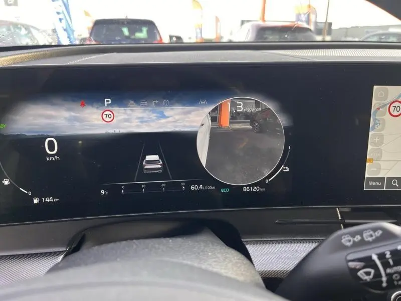 Tableau de bord numérique du Kia Sportage blanc, affichant la vitesse à 0 km/h et caméra de recul active.