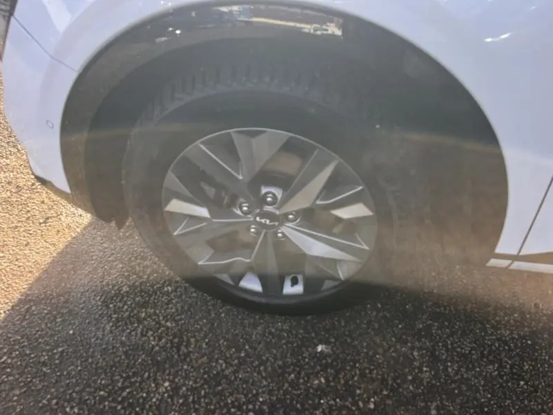 Gros plan sur la roue avant gauche avec jante alliage gris du Kia Sportage blanc nacré 2022.