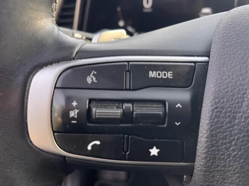 Gros plan sur les commandes audio et téléphone au volant cuir noir du KIA SPORTAGE blanc nacré 2022, côté gauche.