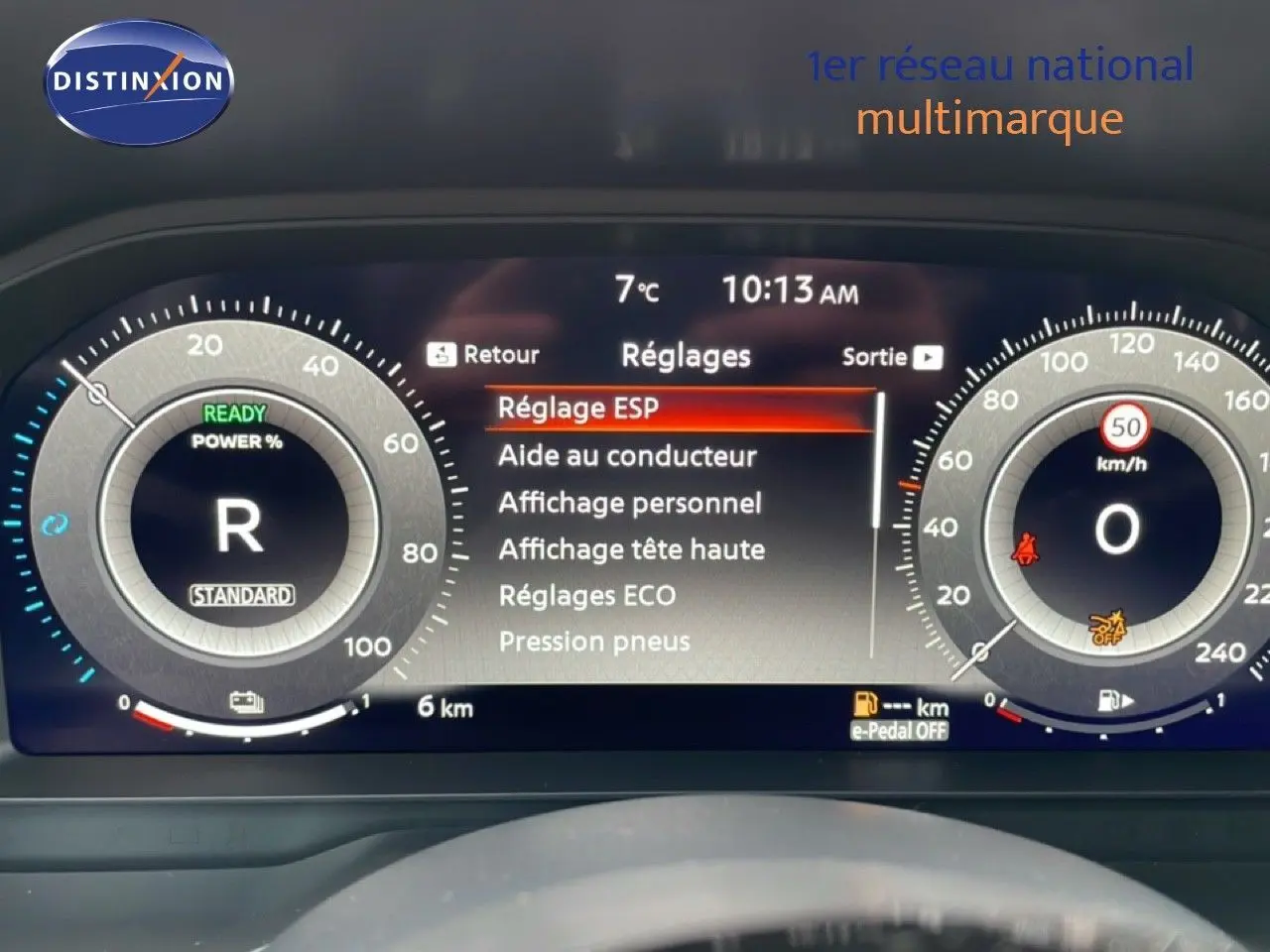 Tableau de bord numérique du Nissan Qashqai blanc nacré, affichant les réglages et la vitesse à 0 km/h.