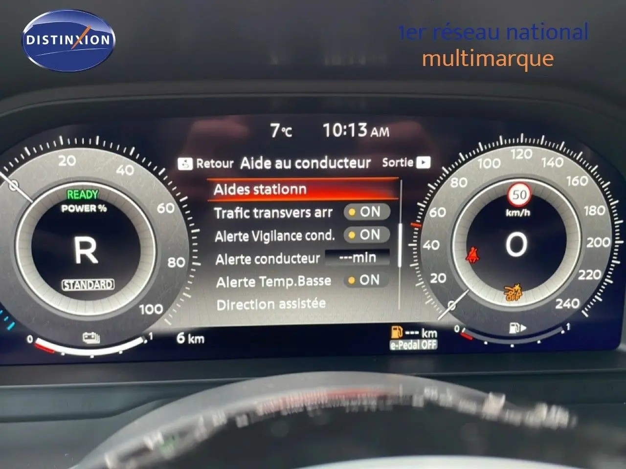 Tableau de bord numérique du Nissan Qashqai blanc nacré, affichant les aides au conducteur et la vitesse à 0 km/h.