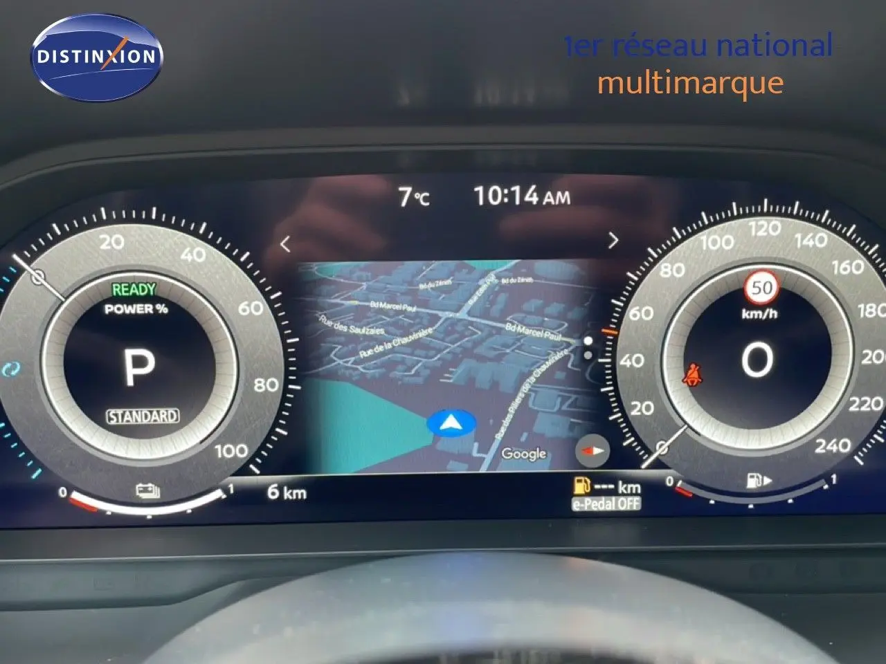 Tableau de bord numérique du Nissan Qashqai blanc nacré, affichant la navigation et les compteurs à 10:14 AM.