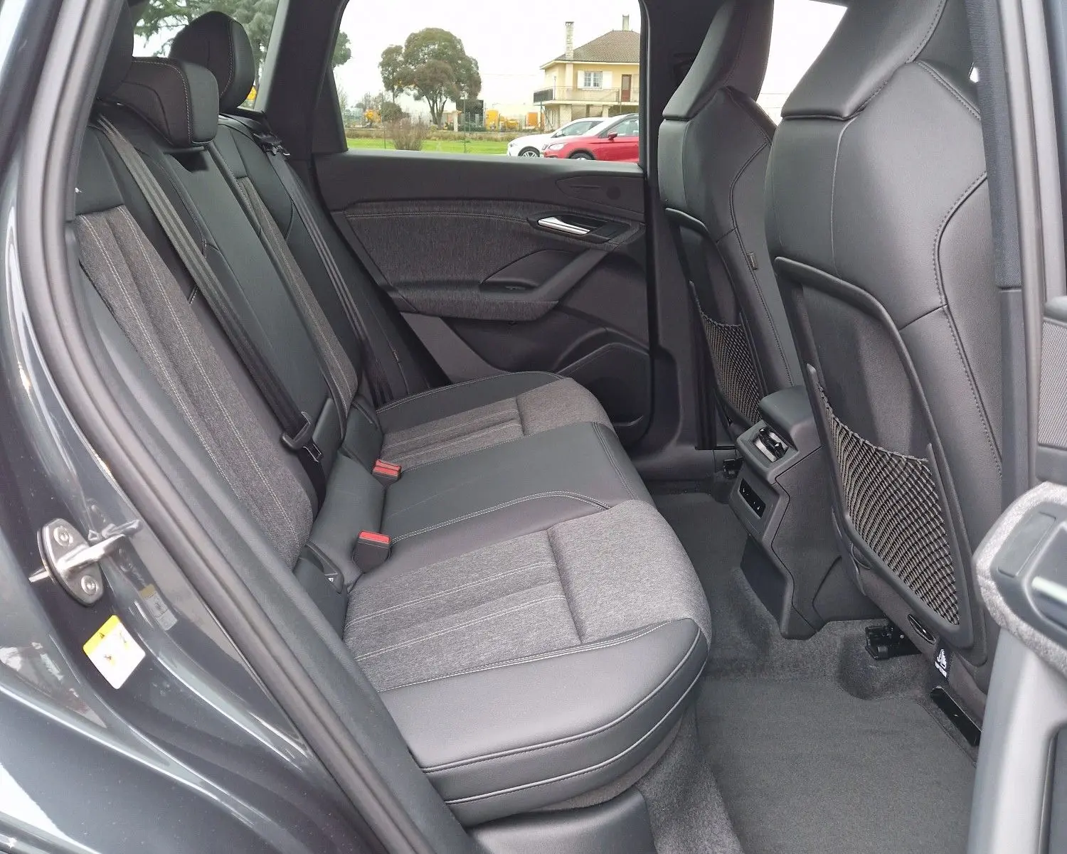 Vue intérieure côté gauche montrant la banquette arrière en tissu et cuir de l'Audi Q6 e-tron Performance S-Line gris Manhattan.