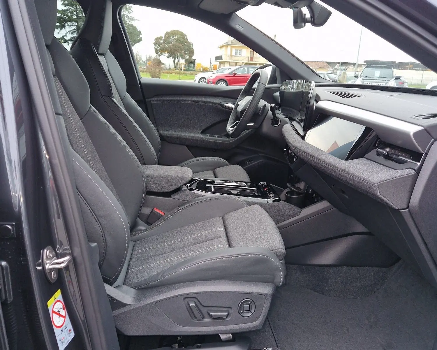 Intérieur côté conducteur de l'Audi Q6 e-tron Performance S-Line 2025 en gris Manhattan, sièges sport et tableau de bord moderne.