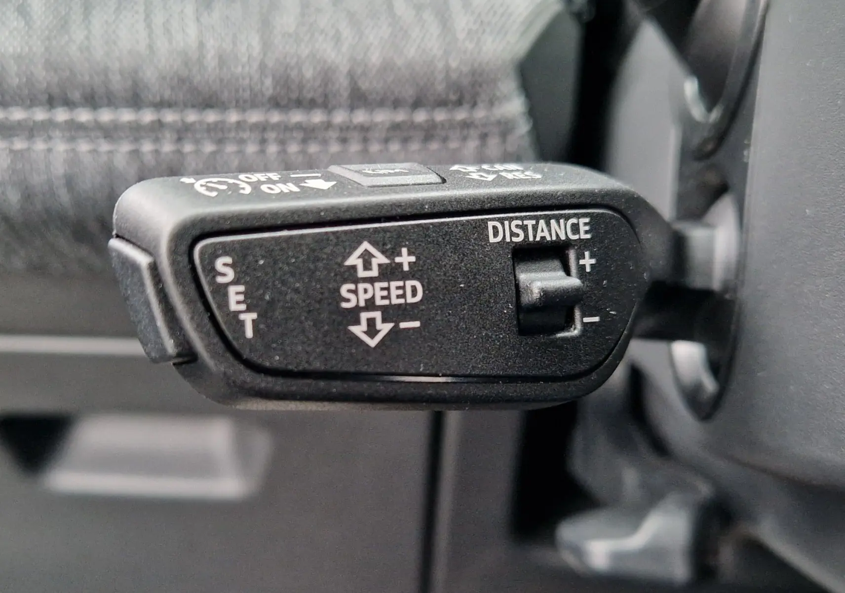 Gros plan sur la commande de régulateur de vitesse adaptatif dans l'habitacle de l'Audi Q6 e-tron gris Manhattan.