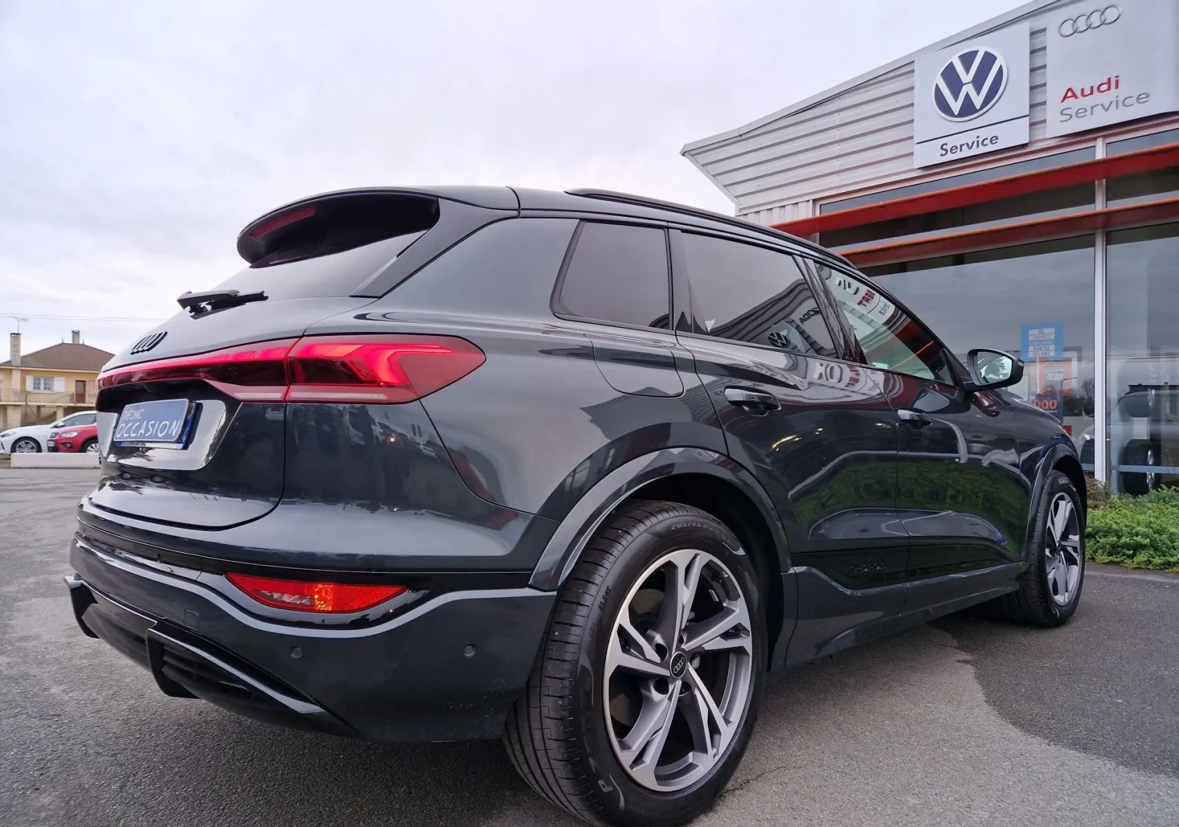 Audi Q6 e-tron Performance S-Line gris Manhattan vu en 3/4 arrière droit, avec jantes Audi Sport et détails noirs.