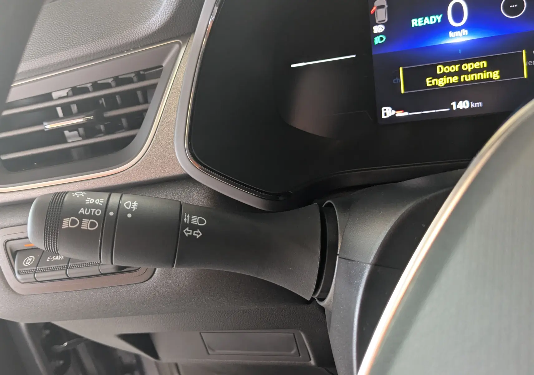 Gros plan sur la commande des feux et clignotants à gauche du volant du Renault Captur hybride, tableau de bord numérique visible.