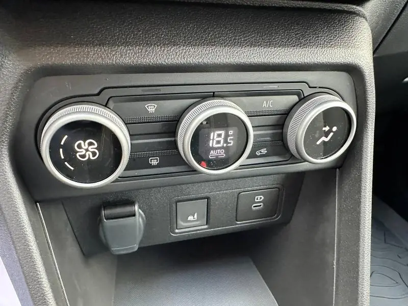 Gros plan sur les commandes de climatisation du DACIA SANDERO 2025, avec affichage digital et boutons rotatifs noirs.