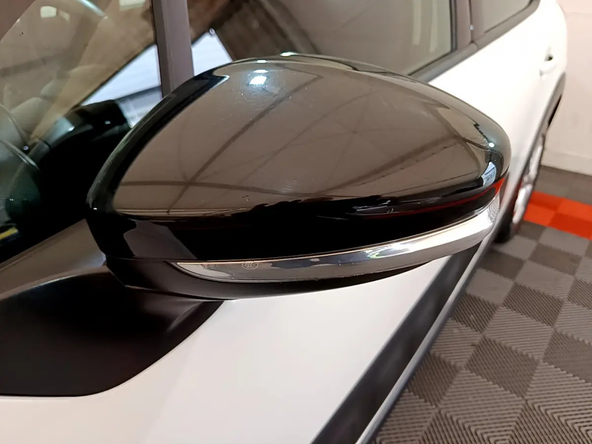 Gros plan sur le rétroviseur droit noir brillant d'une Citroën C3 blanche vue de côté, avec clignotant intégré.