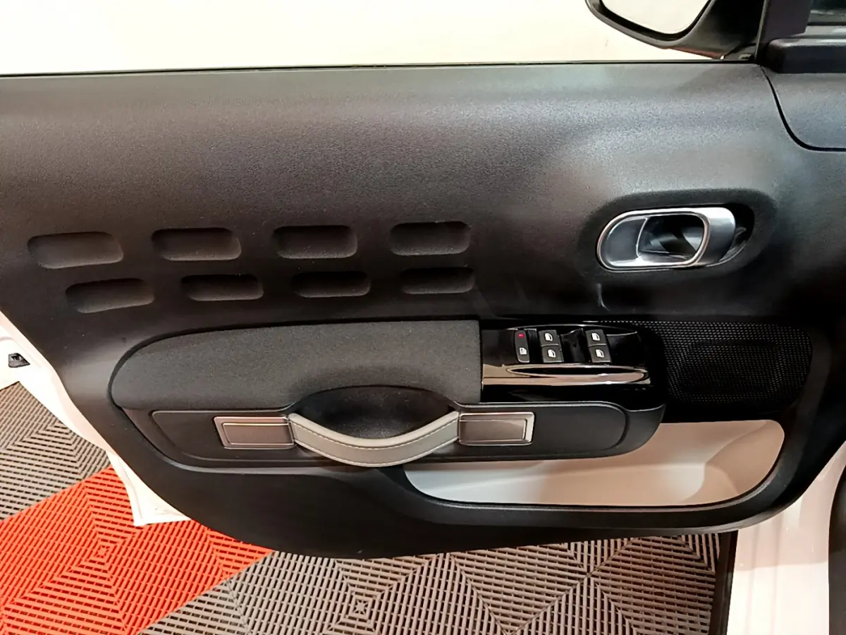 Gros plan sur la porte avant gauche blanche d'une Citroën C3 2019 avec commandes de vitres et poignée noire.