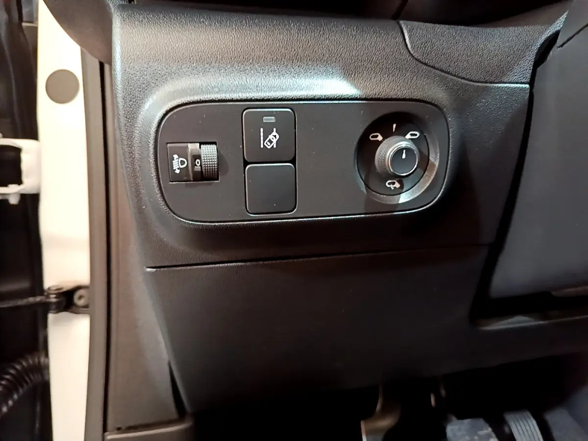 Vue rapprochée des commandes de réglage des phares et rétroviseurs côté conducteur d'une Citroën C3 blanche de 2019.