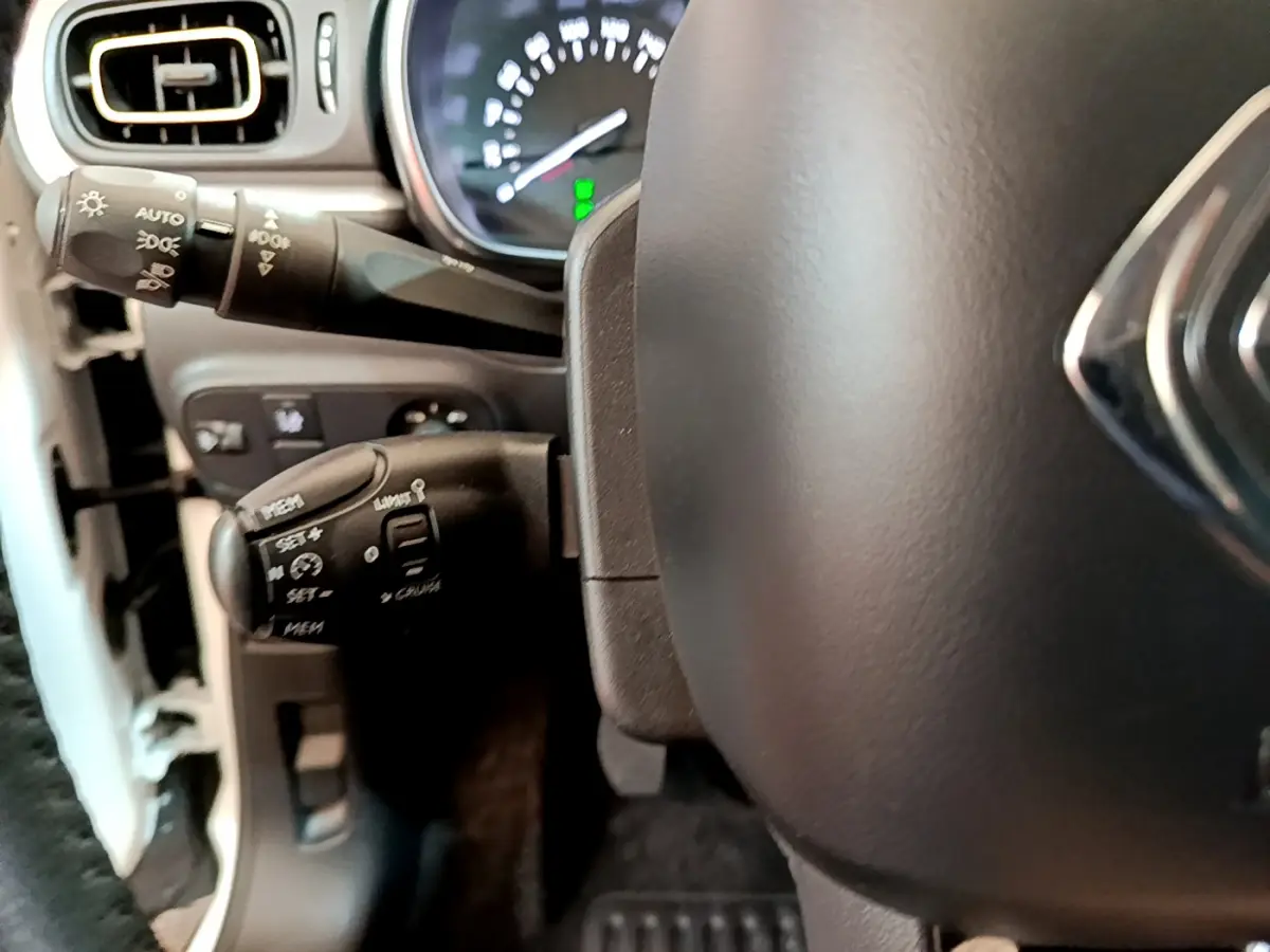 Gros plan sur le volant cuir et commandes au volant côté gauche d'une Citroën C3 blanche de 2019.