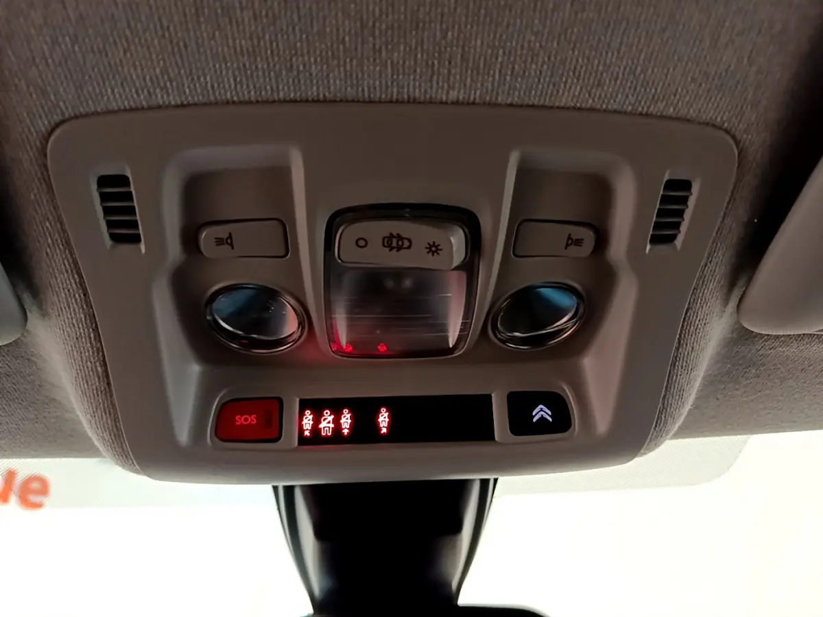 Vue en plongée du plafonnier gris clair de la Citroën C3 avec boutons SOS et éclairage intérieur allumé.