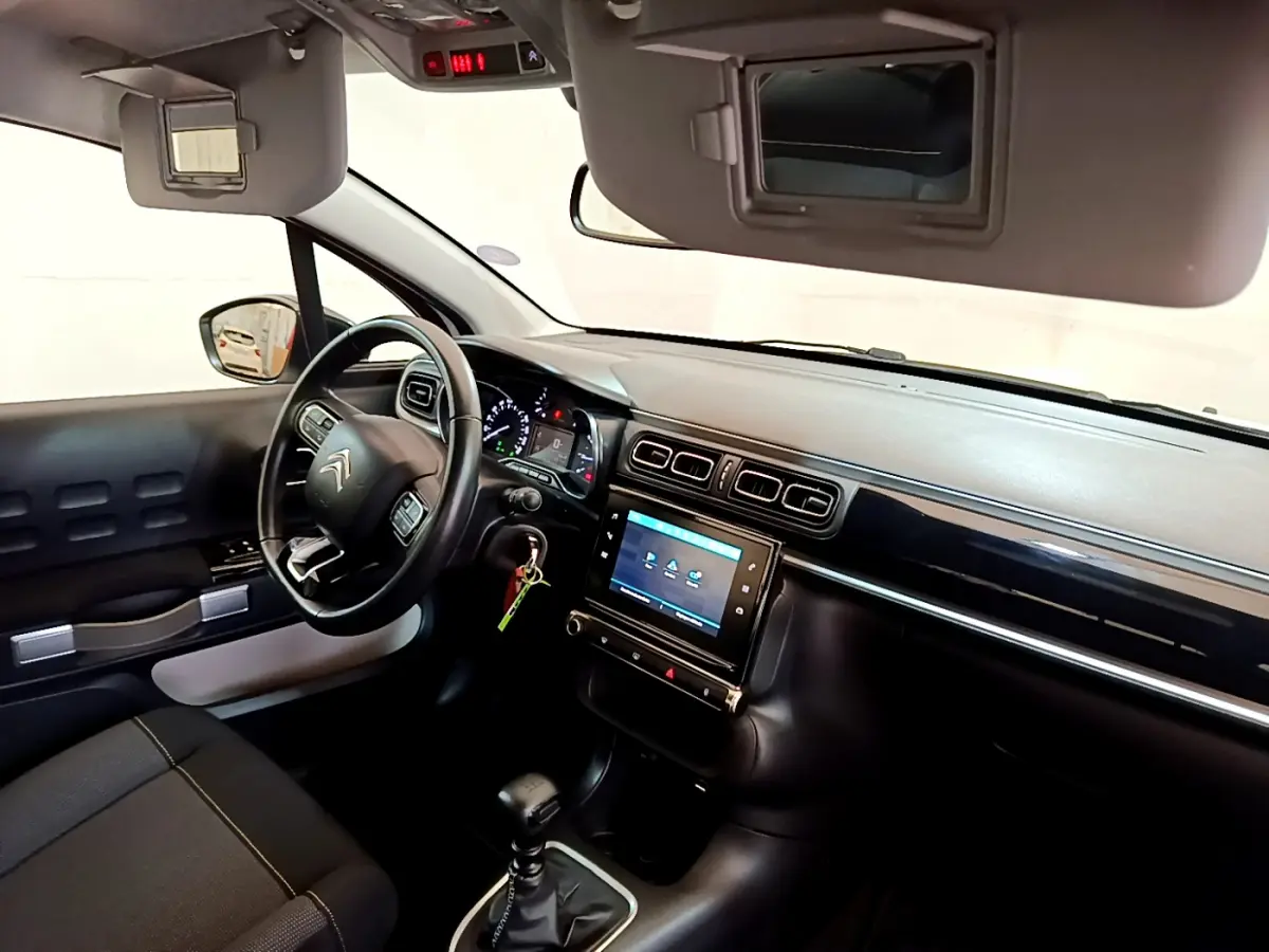 Intérieur de la Citroën C3 blanche, vue côté conducteur, tableau de bord avec écran tactile et volant cuir multifonctions.