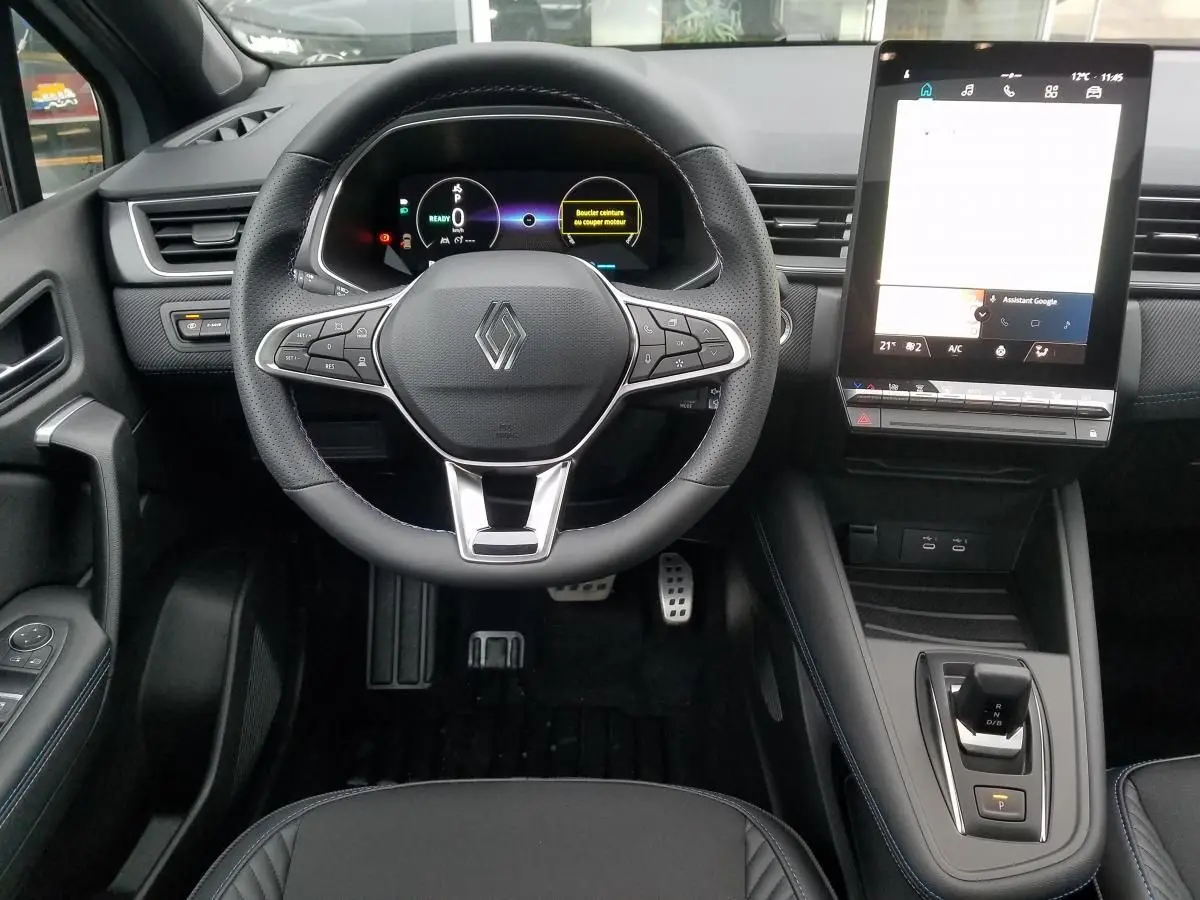 Vue intérieure du tableau de bord du Renault Captur gris Rafale 2025, avec volant multifonction et écran tactile vertical.