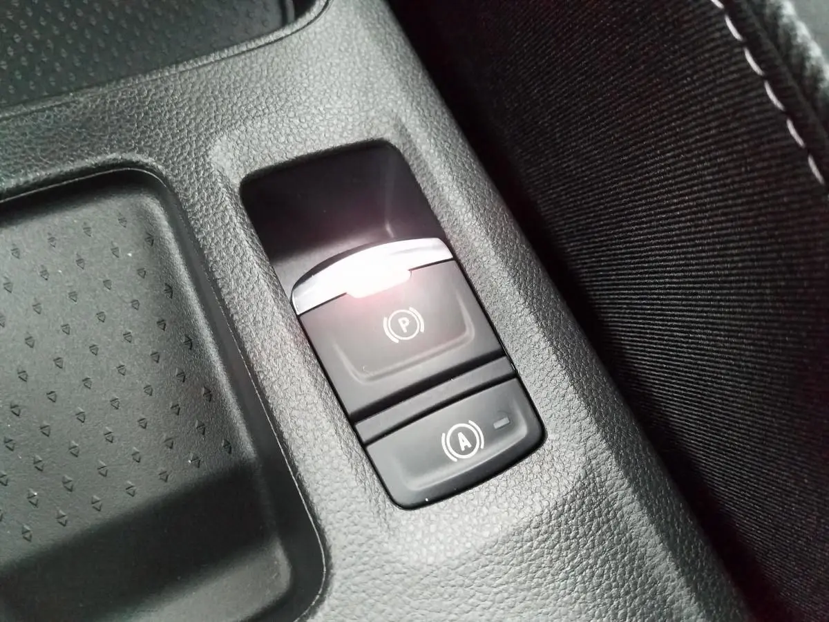 Gros plan sur les boutons du frein de parking électrique et de la fonction Auto-Hold dans la console centrale du Renault Captur gris Rafale.