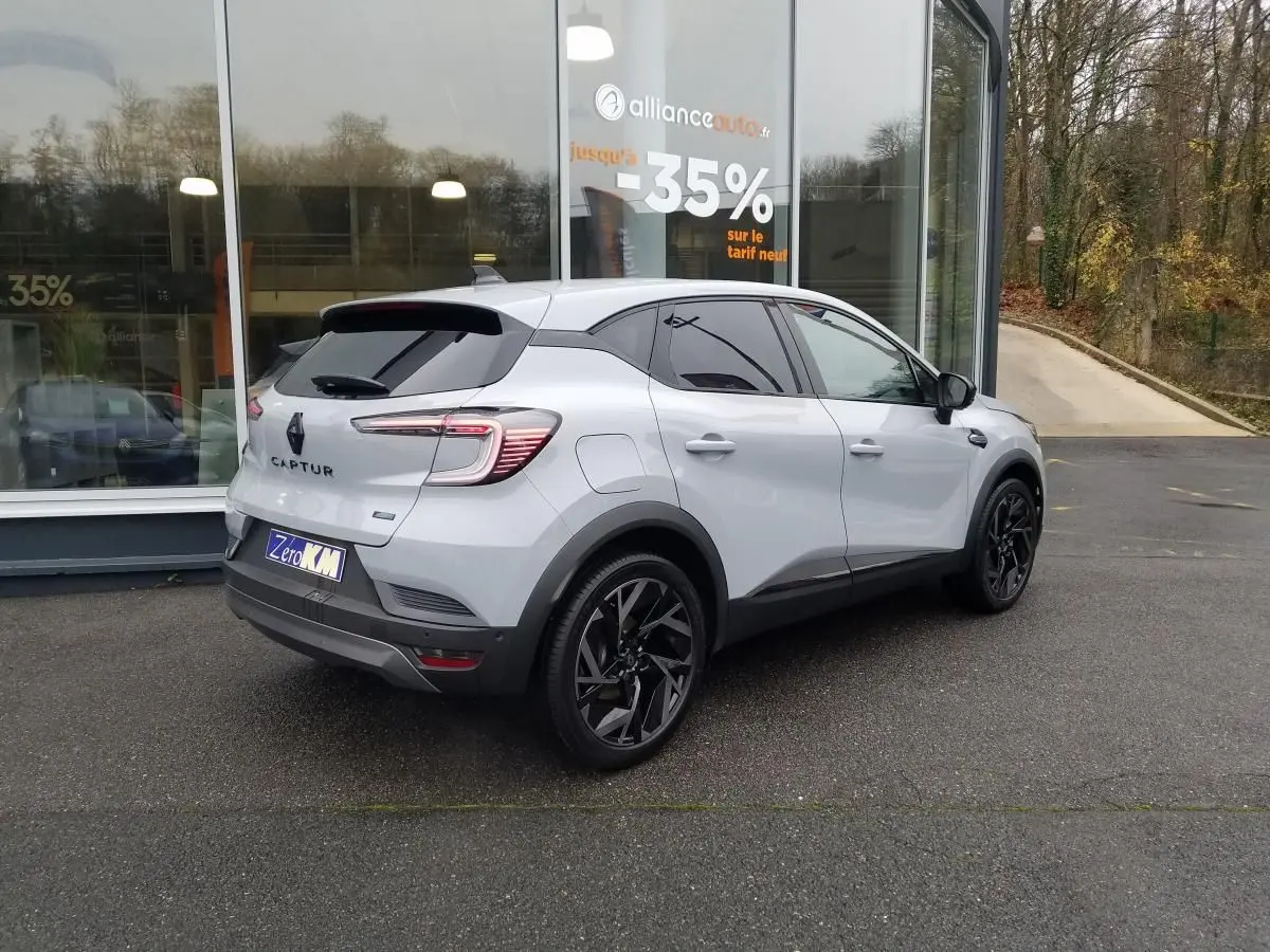 Renault Captur gris Rafale en 3/4 arrière droit, toit ouvrant noir brillant et jantes 19 pouces noires.