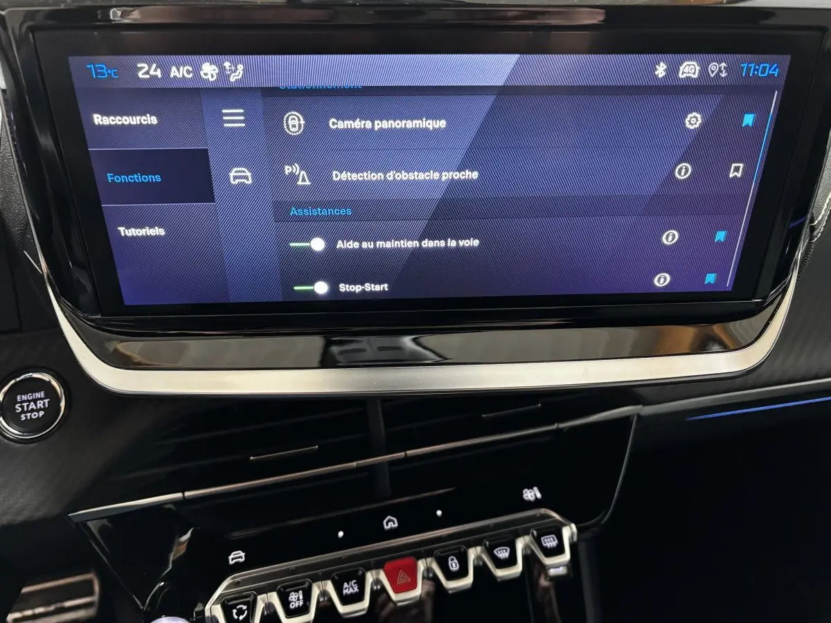 Écran tactile central affichant les aides à la conduite dans l’habitacle d’une Peugeot 208 Hybrid gris clair.