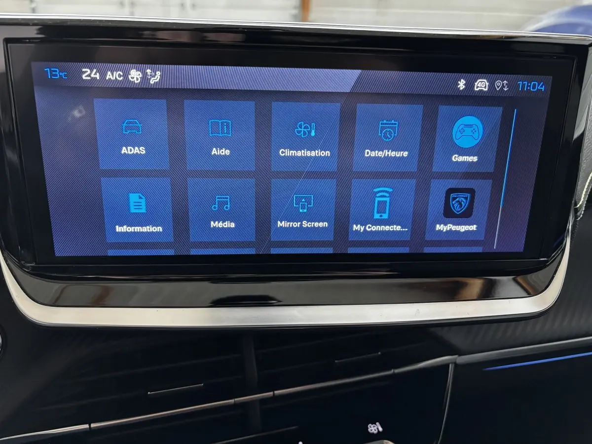 Écran tactile central affichant les options multimédia et climatisation dans l’habitacle d’une Peugeot 208 Hybrid 110 e-DCS6 GT gris clair.