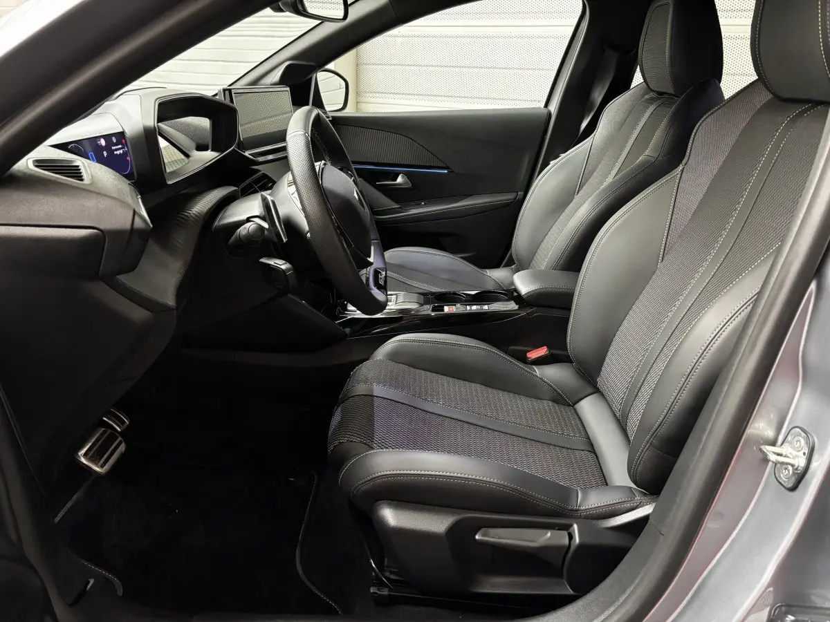 Intérieur avant droit de la Peugeot 208 Hybrid gris clair, sièges cuir et tableau de bord avec écran tactile.