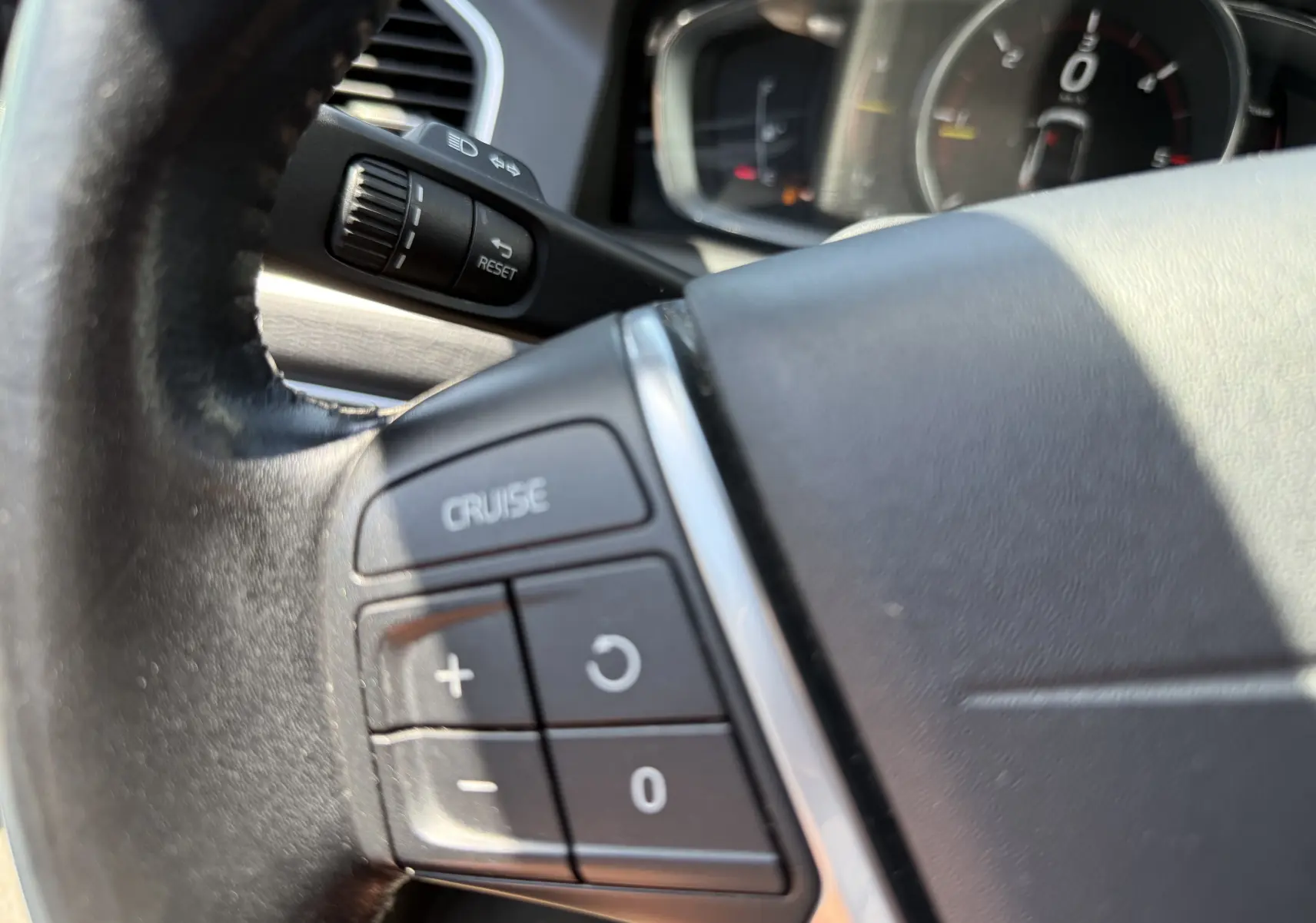 Gros plan sur les commandes de régulateur de vitesse au volant cuir noir du Volvo XC60 gris foncé, version 2016.
