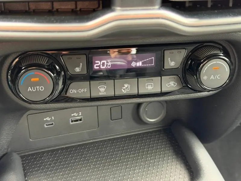 Tableau de bord du Nissan Juke 2025 montrant la commande de climatisation automatique et ports USB en gros plan.