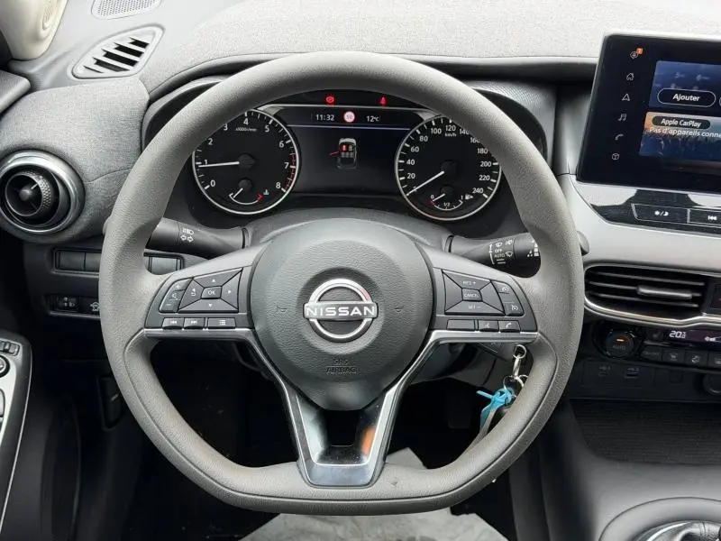 Vue rapprochée du volant multifonction noir du Nissan Juke 2025 avec tableau de bord et écran tactile visibles.